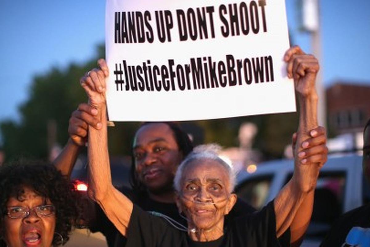 Protesters in Ferguson with placards reading “Hands up, don’t shoot”