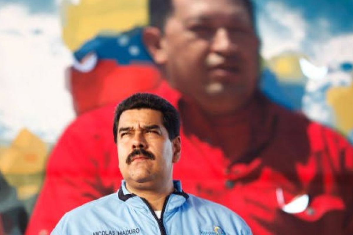O presidente Nicolás Maduro diante de um retrato de Hugo Chávez